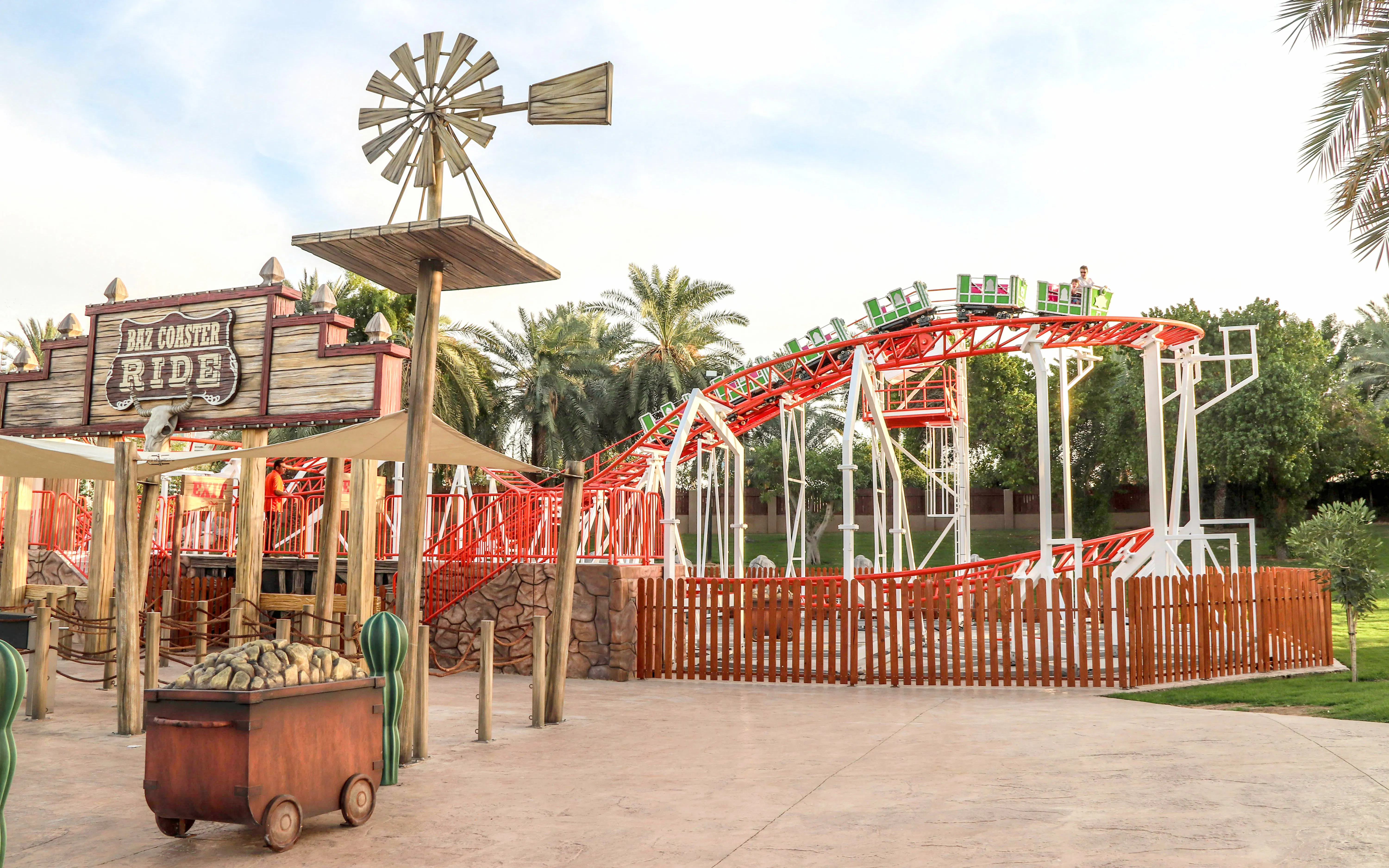 Baz Coaster ride at Al Montazah Parks, featuring red tracks and green cars.