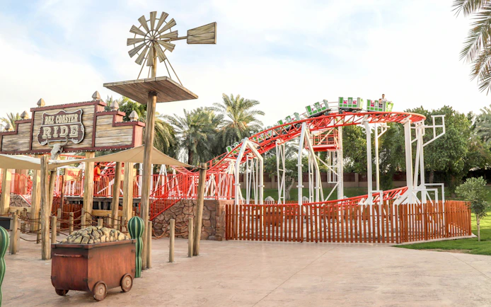 Baz Coaster ride at Al Montazah Parks, featuring red tracks and green cars.