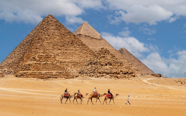 Tourists on camels near the Pyramids of Giza, Cairo, during a full-day trip from Hurghada.