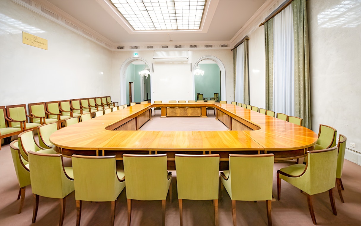 Palace of Culture and Science conference room with large wooden table and green chairs.