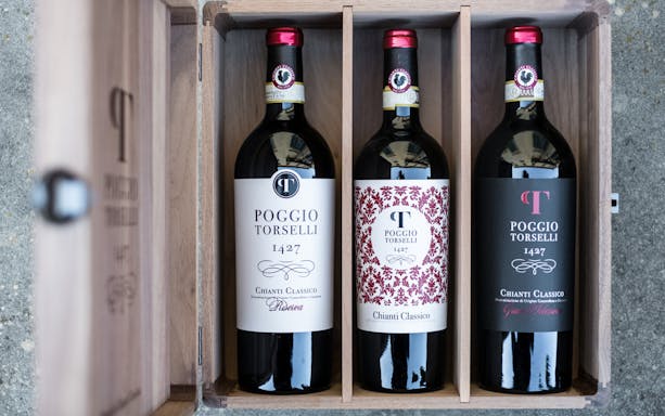 Three bottles of Poggio Torselli Chianti Classico wine in a wooden box, Tuscany tour.