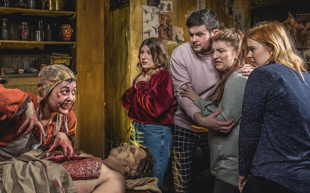 Visitors react to a costumed actor in a dramatic scene at the Edinburgh Dungeon Tour.