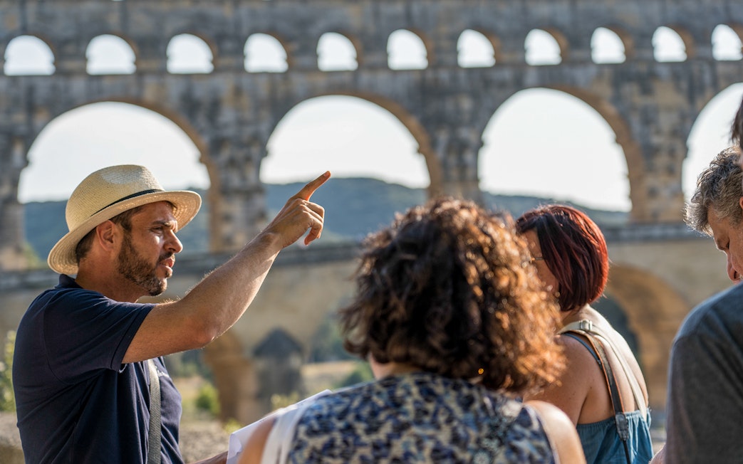 Tour guide explaining Pont du Gard to visitors in Provence.