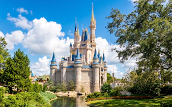 Castle at Walt Disney Resort Orlando with blue spires and surrounding greenery.