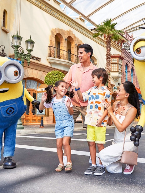 Family interacting with Minion characters at Universal Studios Singapore entrance.