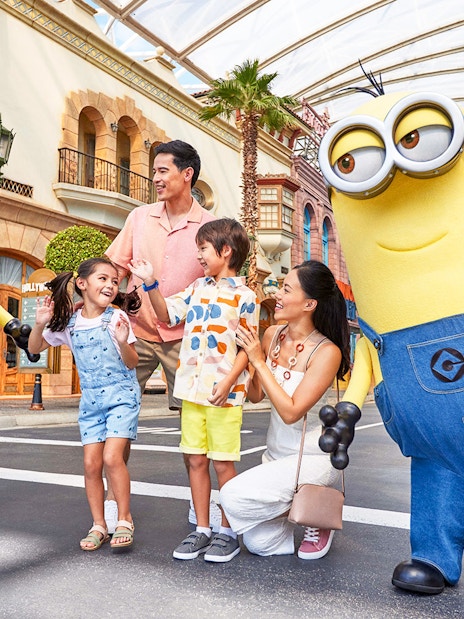 Family interacting with Minion characters at Universal Studios Singapore entrance.