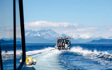 Boat on Alaskan waters with snowy mountains, Juneau.