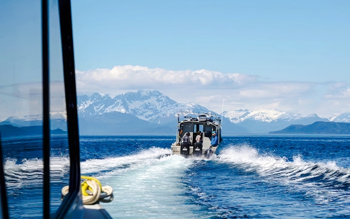 Boat on Alaskan waters with snowy mountains, Juneau.
