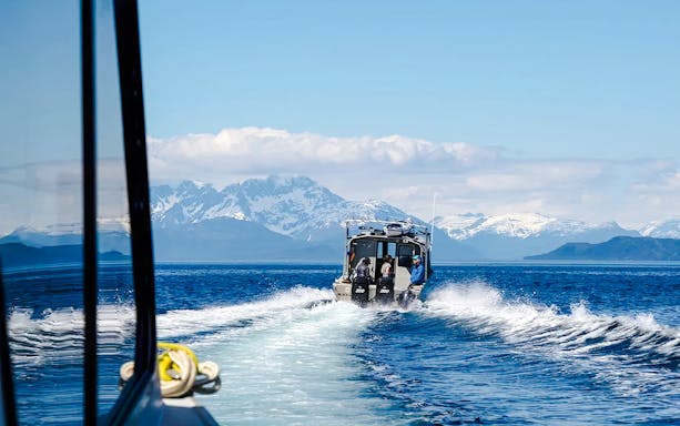 Boat on Alaskan waters with snowy mountains, Juneau.