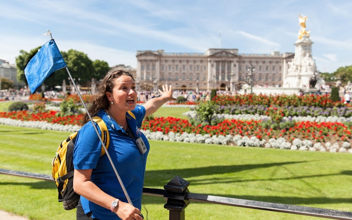 Tour guide leading a group near Buckingham Palace gardens, London.