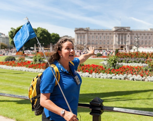 Tour guide leading a group near Buckingham Palace gardens, London.