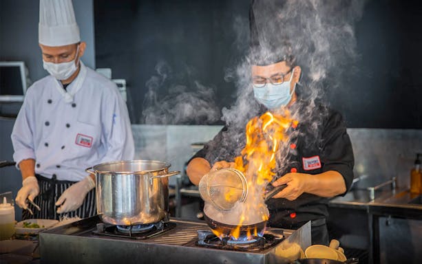 Chefs preparing a flaming dish at Baiyoke Sky Hotel's festive dinner event.
