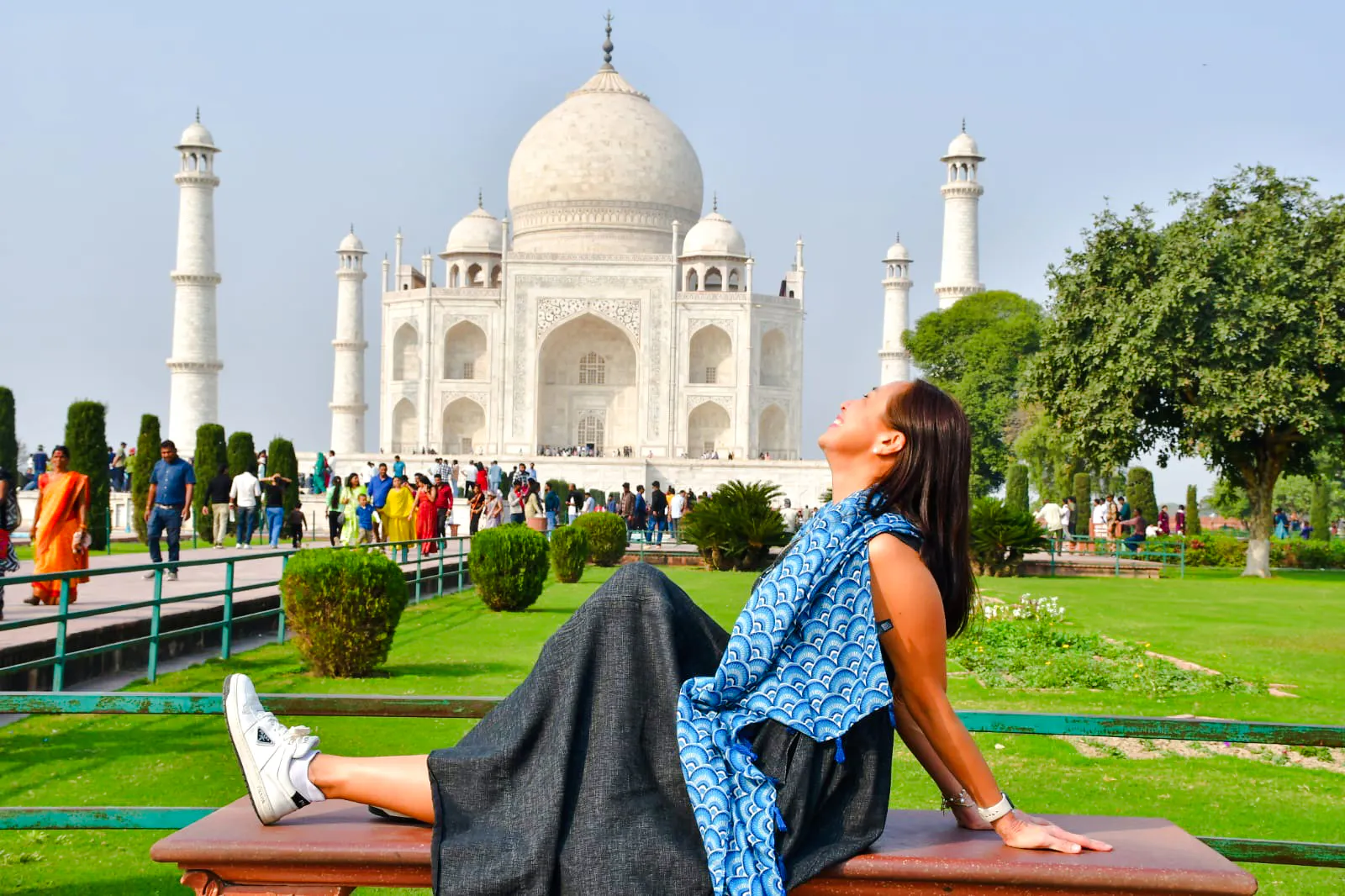 Woman relaxing on a bench with the Taj Mahal in the background, Agra tour.