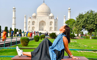 Woman relaxing on a bench with the Taj Mahal in the background, Agra tour.
