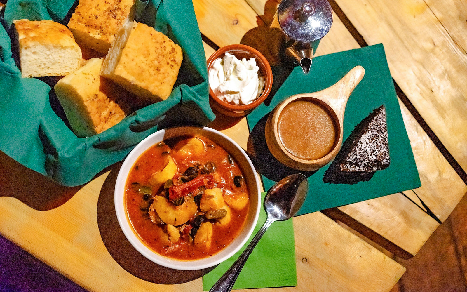 Traditional Alaskan meal with stew, bread, and dessert in a Gamme hut setting.