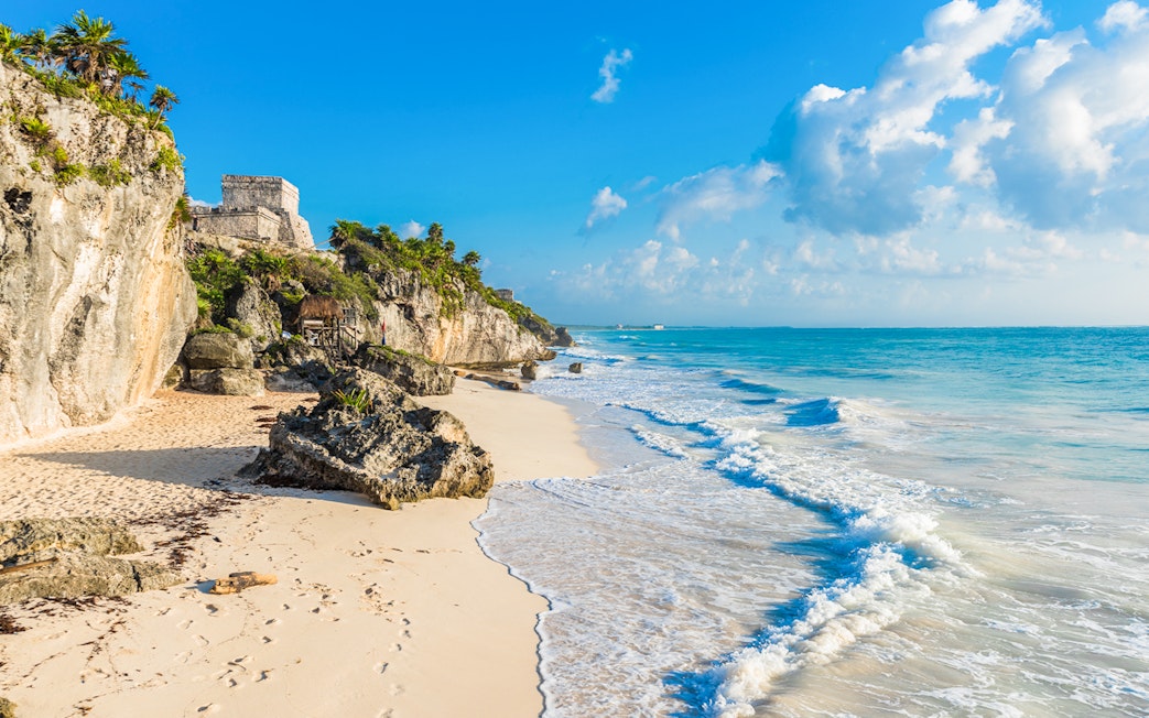 White sand beach with Tulum ruins on cliffs, Yucatan, Mexico.