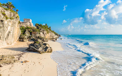 White sand beach with Tulum ruins on cliffs, Yucatan, Mexico.