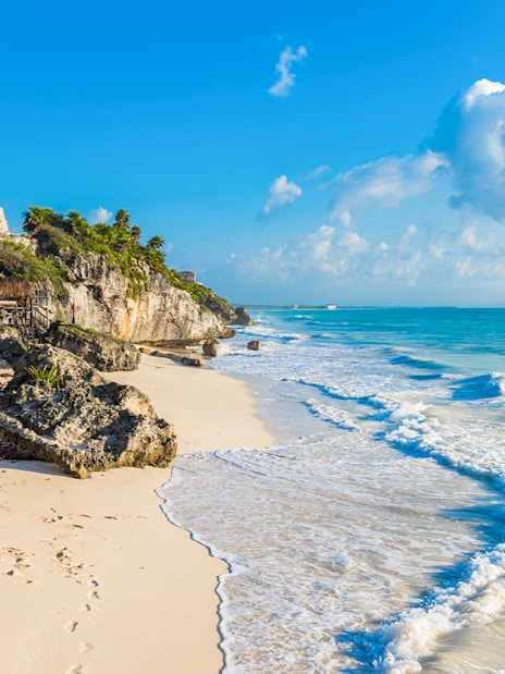 White sand beach with Tulum ruins on cliffs, Yucatan, Mexico.