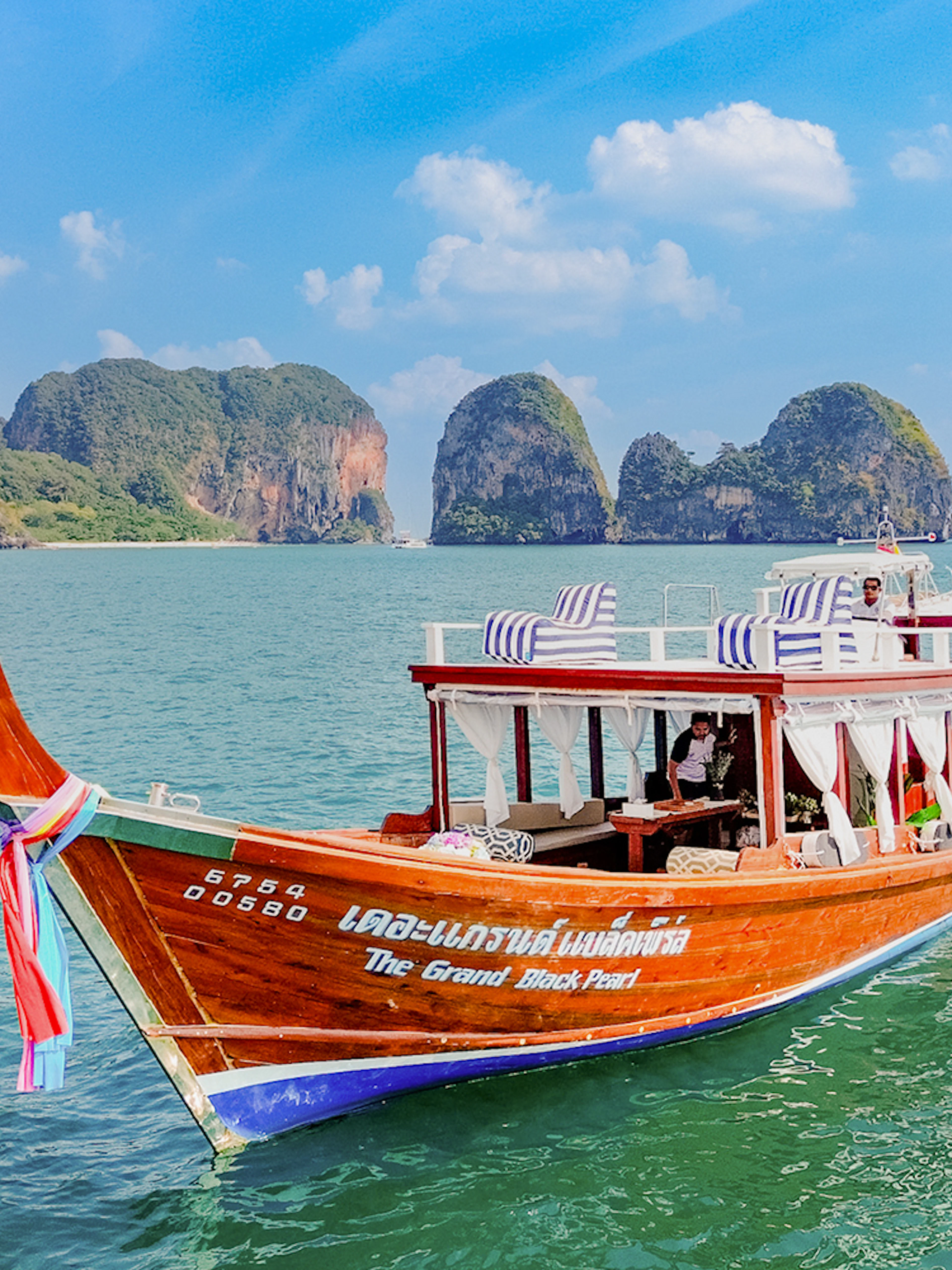 Long tail boat on the water near limestone cliffs, Ko Hong, Thailand.