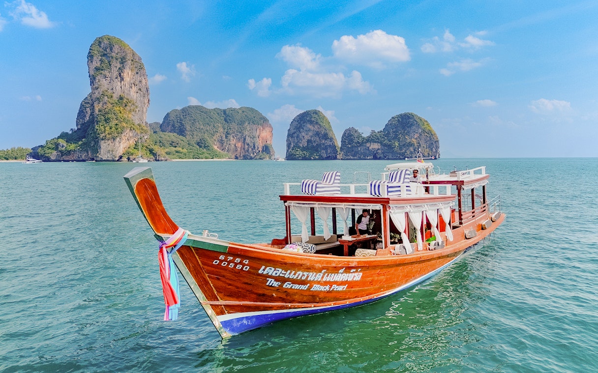 Long tail boat on the water near limestone cliffs, Ko Hong, Thailand.