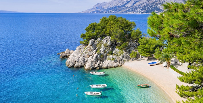 Boats anchored near a rocky cove with clear blue water at Blue Lagoon, Croatia.