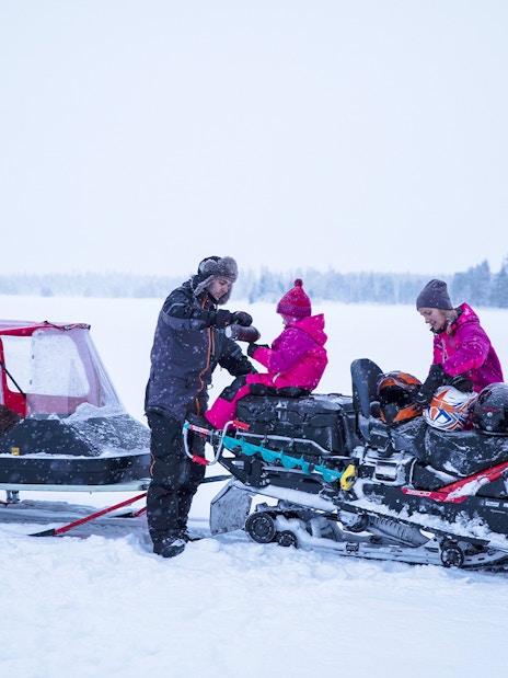 Snowmobile tour group in snowy landscape preparing for Northern Lights excursion.
