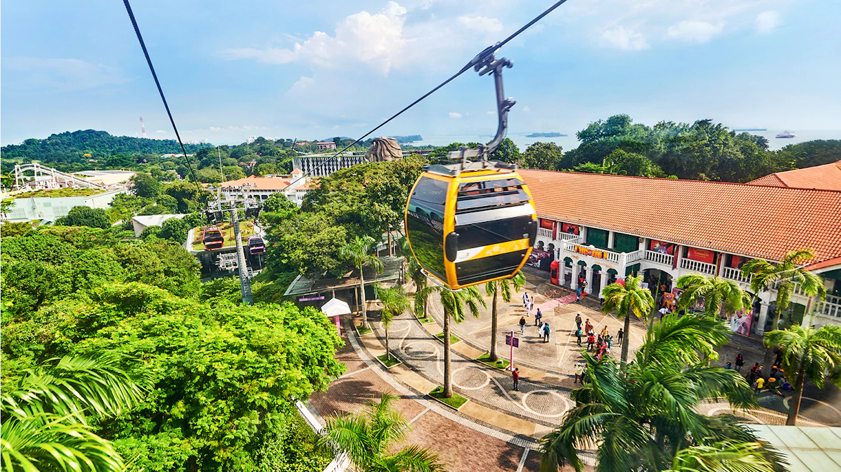Aerial view of Singapore cityscape from a cable car, highlighting lush greenery and urban architecture.