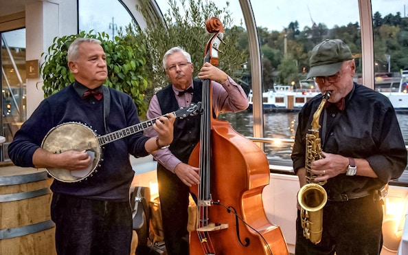 Musicians playing banjo, double bass, and saxophone on a Prague dinner cruise with live music.