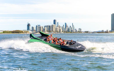 Group enjoying a jet boat ride with Gold Coast skyline in the background, Australia.