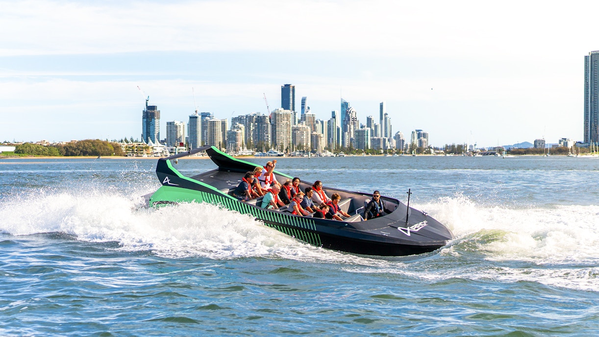 Group enjoying a jet boat ride with Gold Coast skyline in the background, Australia.