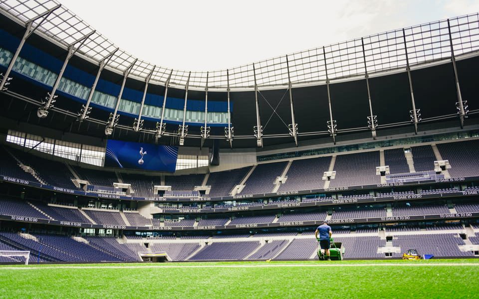Groundskeeper maintaining the field at a large, modern stadium.
