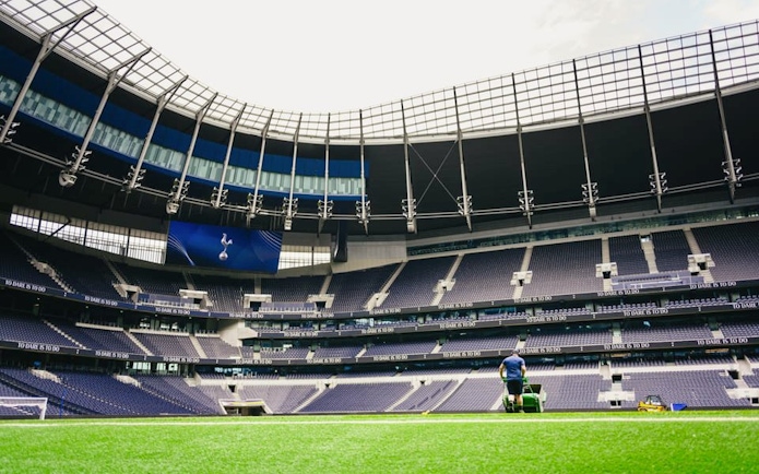 Groundskeeper maintaining the field at a large, modern stadium.