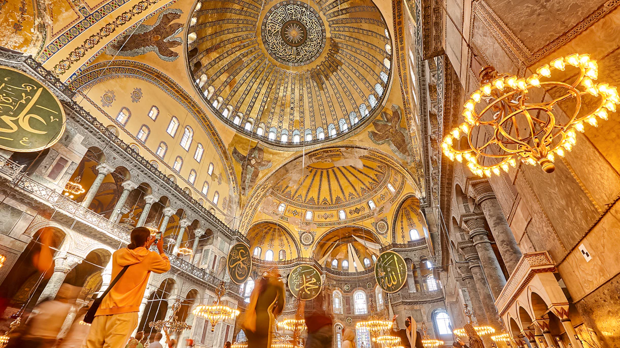 Hagia Sophia interior with ornate dome and visitors, Istanbul.