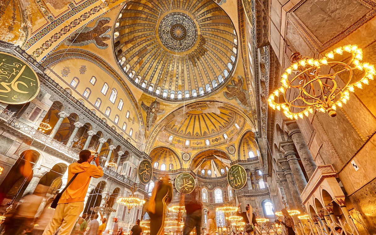 Hagia Sophia interior with ornate dome and visitors, Istanbul.