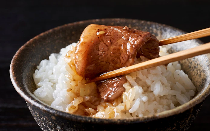 Chopsticks holding A5 Wagyu beef over rice, Tokyo Omakase Sushi & A5 Wagyu Premium Foodie Tour.