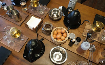 Vietnamese egg coffee preparation setup with eggs, coffee tools, and ingredients on a wooden table.