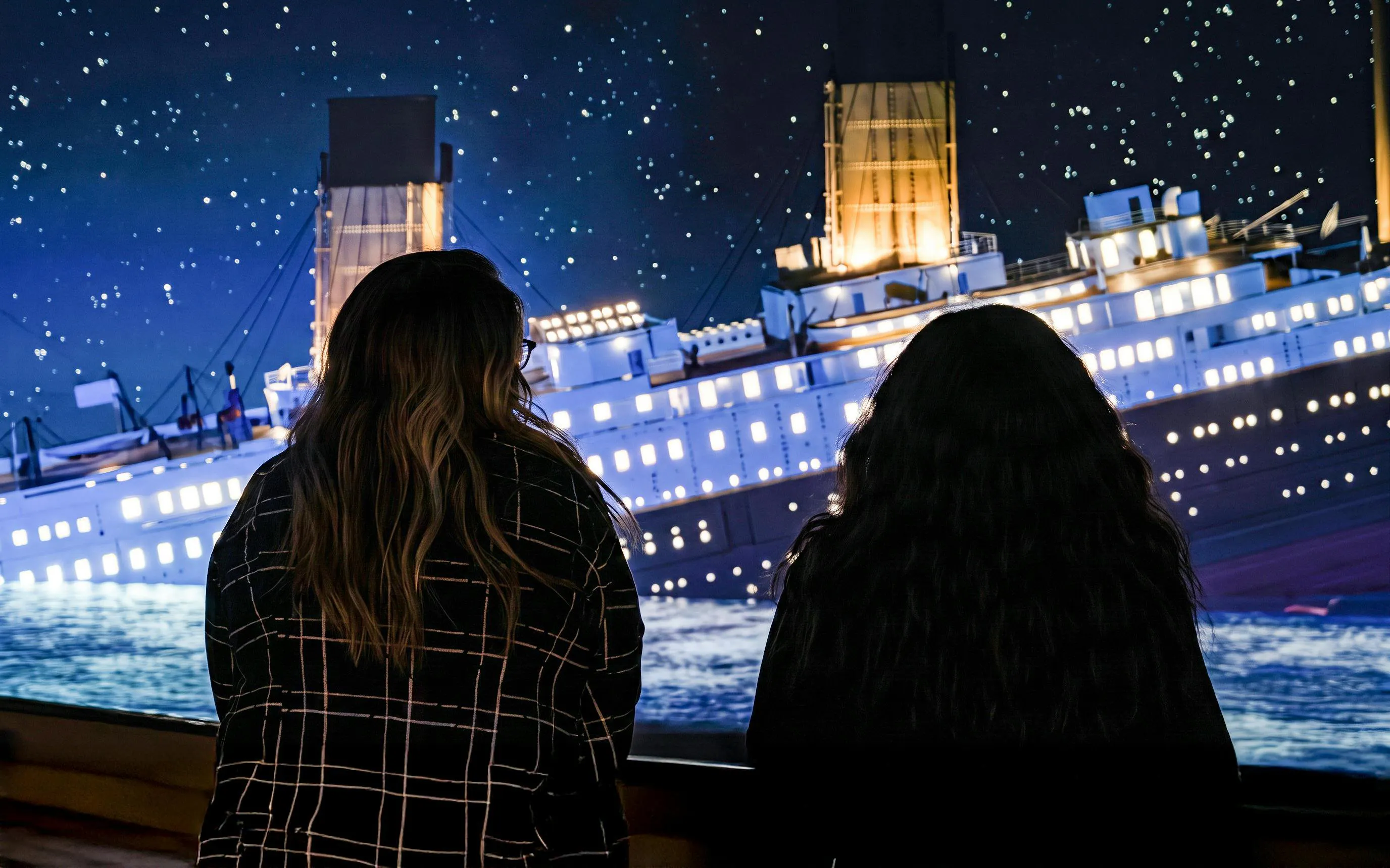 Visitors viewing Titanic exhibit at night in Utrecht.