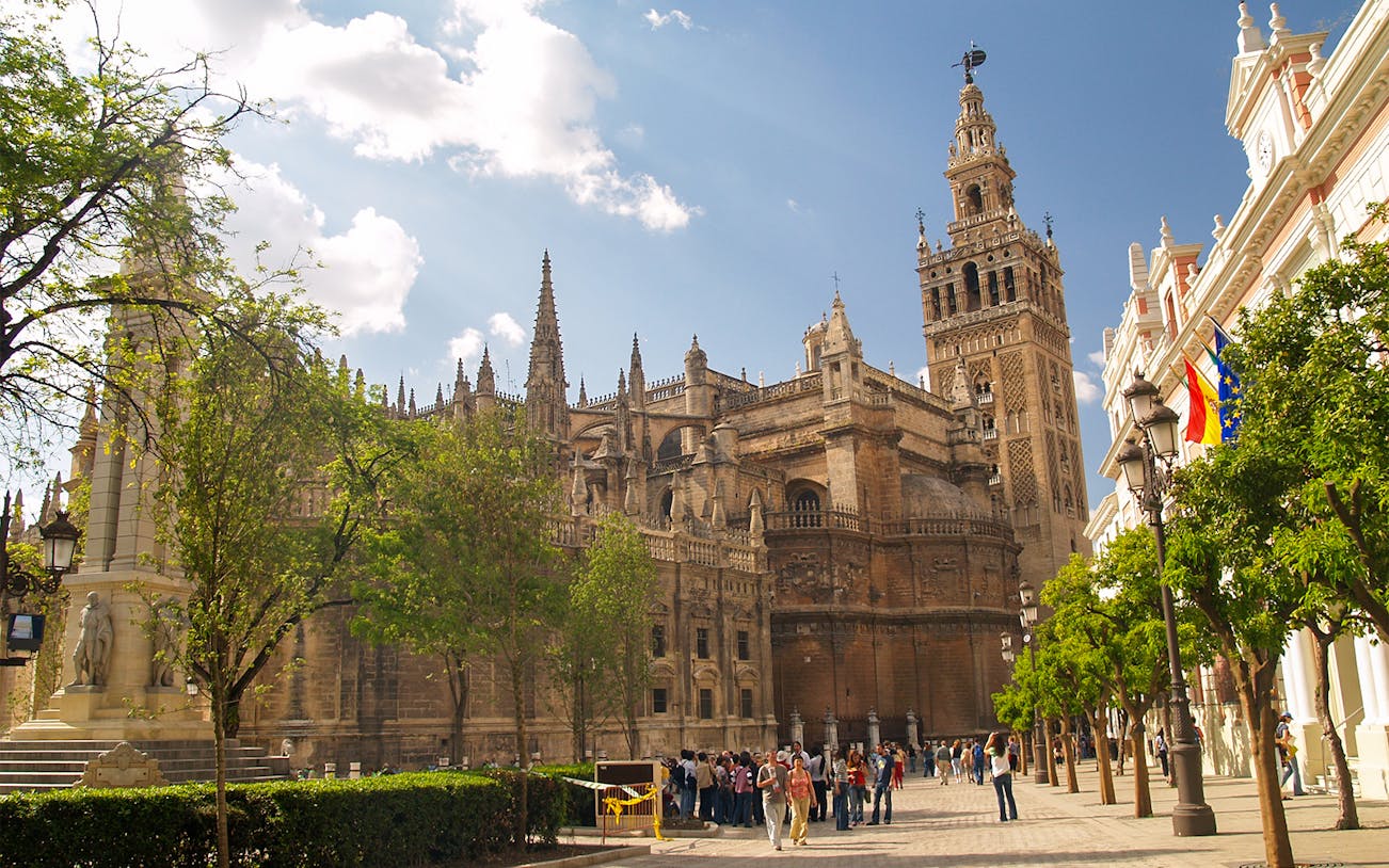 Seville Cathedral with tourists in the foreground, showcasing Gothic architecture.