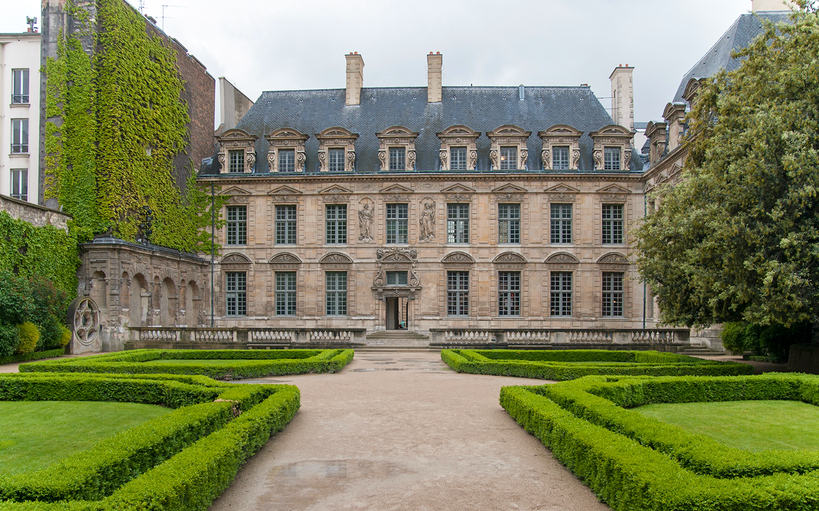 Hotel de Sully courtyard with manicured hedges and historic architecture, Paris.