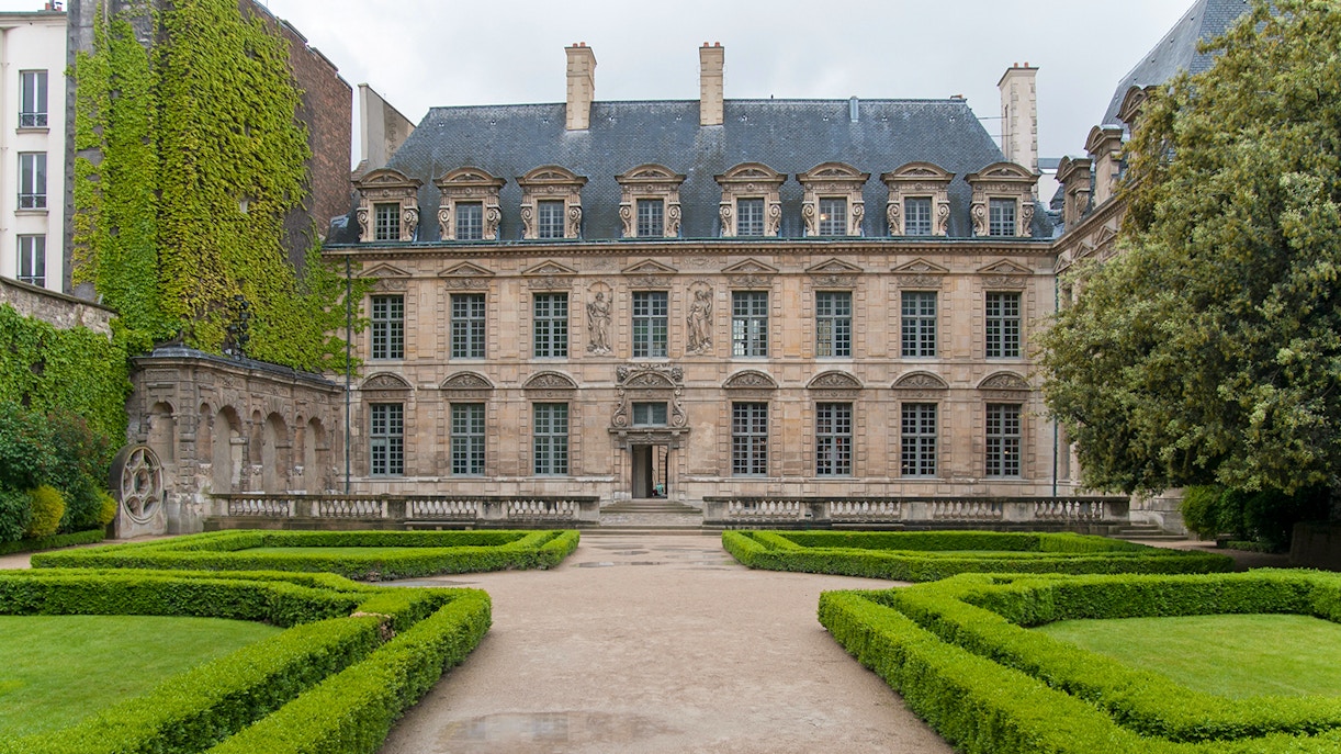 Hotel de Sully courtyard with manicured hedges and historic architecture, Paris.