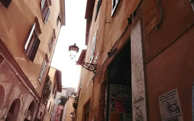 Narrow alleyway with historic buildings and street lamp in Pisa, part of the Romantic Walk exploration game.