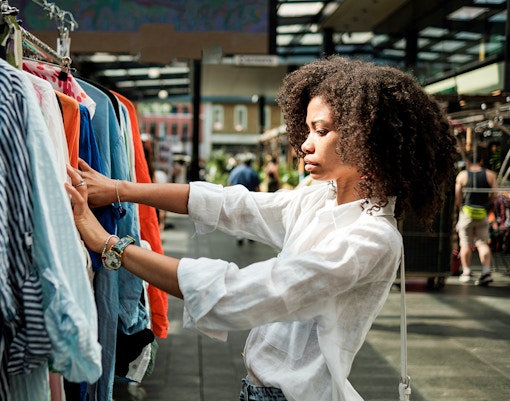 Shopping at a London market, browsing colorful clothes on a rack.