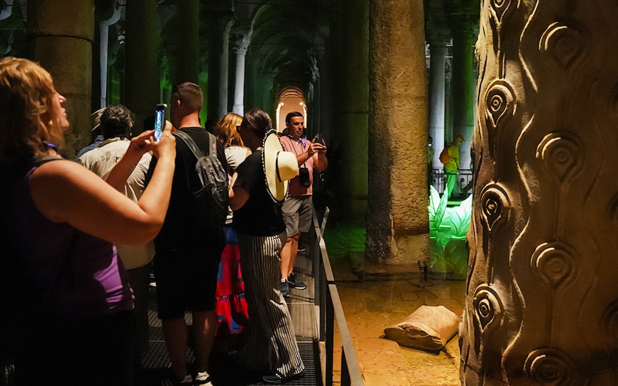 Visitors exploring the Basilica Cistern with illuminated columns in Istanbul.