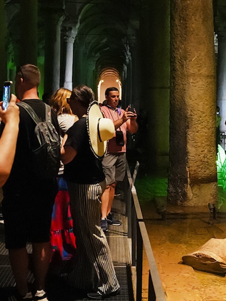 Visitors exploring the Basilica Cistern with illuminated columns in Istanbul.
