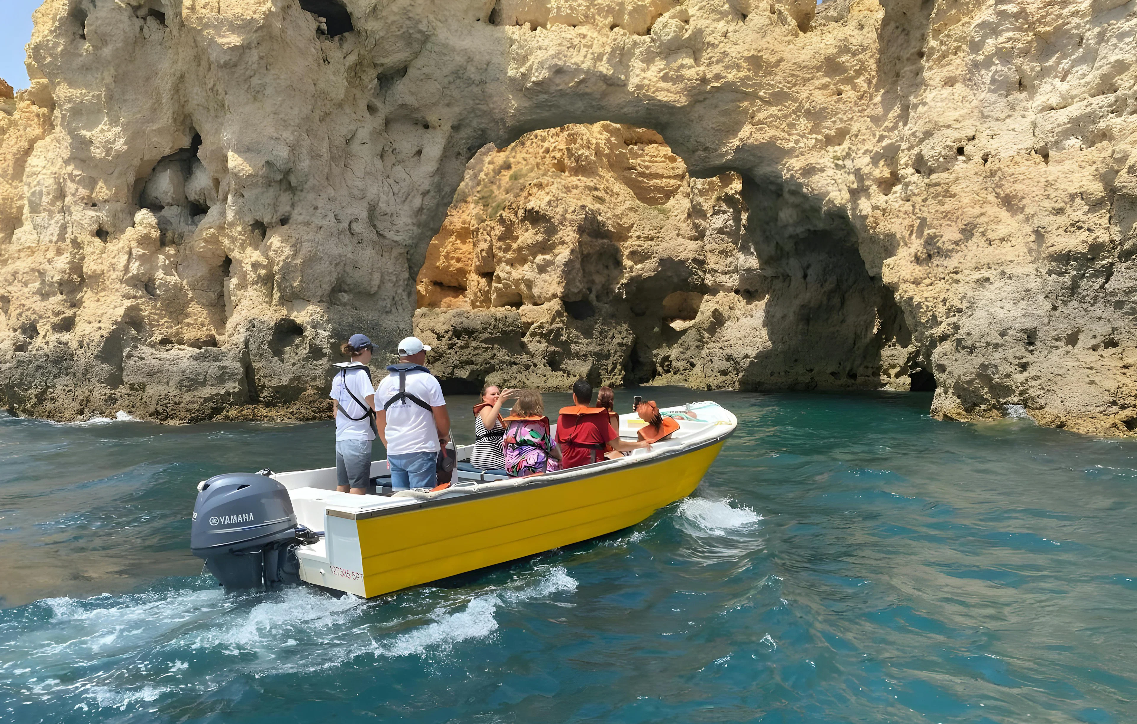 Tourists on a boat exploring Ponta da Piedade's rock formations in Lagos, Portugal.