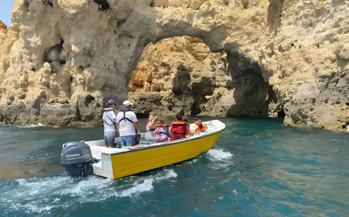 Tourists on a boat exploring Ponta da Piedade's rock formations in Lagos, Portugal.
