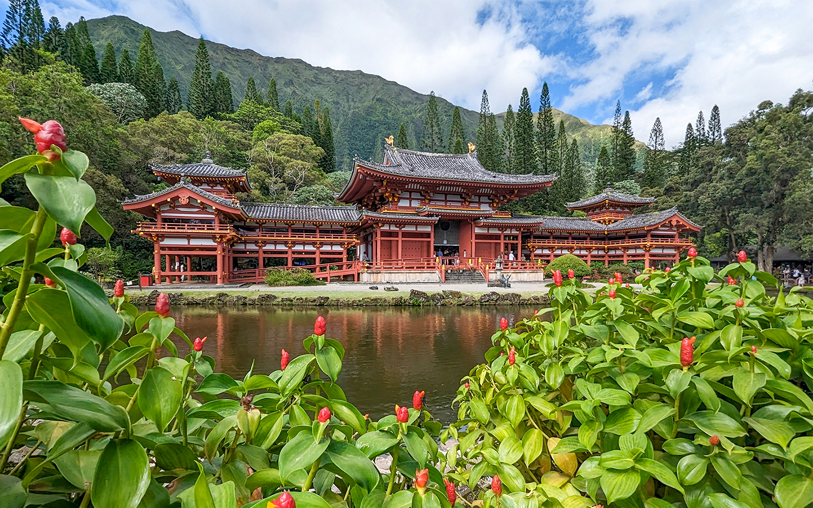 Byodo-In Temple in Oahu, Hawaii with lush greenery and pond in foreground.