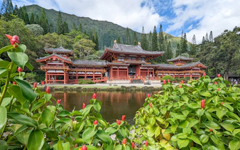 Byodo-In Temple in Oahu, Hawaii with lush greenery and pond in foreground.
