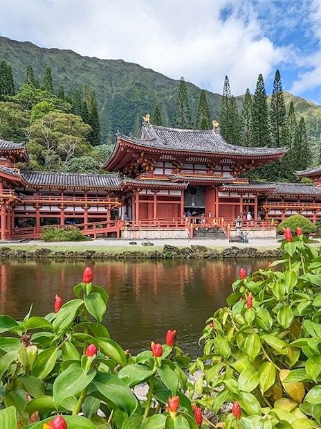 Byodo-In Temple in Oahu, Hawaii with lush greenery and pond in foreground.