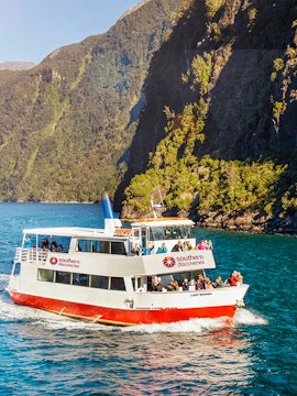 Cruise boat on Milford Sound with scenic mountain backdrop, New Zealand.